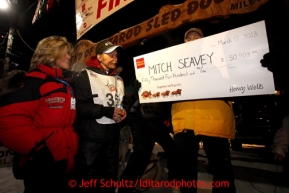 Mitch Seavey, left, 53, with his wife Janine, accepts the winner's check from Greg Deal of Wells Fargo, after pulling into Nome first and winning his second Iditarod sled dog race on Tuesday March 12, 2013. Seavey made the journey from Willow in 9 days, 7 hours, 39 minutes, 56 seconds. Iditarod Sled Dog Race 2013Photo by Jeff Schultz copyright 2013 DO NOT REPRODUCE WITHOUT PERMISSION