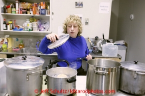 Volunteer Sally Hamm cooks at the Elim checkpoint on Monday March 11, 2013.Iditarod Sled Dog Race 2013Photo by Jeff Schultz copyright 2013 DO NOT REPRODUCE WITHOUT PERMISSION