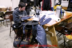 Josh Cadzow changes his boot liners inside the fire hall at the Elim checkpoint on Tuesday March 12, 2013.Iditarod Sled Dog Race 2013Photo by Jeff Schultz copyright 2013 DO NOT REPRODUCE WITHOUT PERMISSION