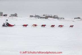 Jason Mackey travels on a lagoon with summer fish houses in the background nearing Nome on Thursday March 13 during the 2014 Iditarod Sled Dog Race.PHOTO (c) BY JEFF SCHULTZ/IditarodPhotos.com -- REPRODUCTION PROHIBITED WITHOUT PERMISSION