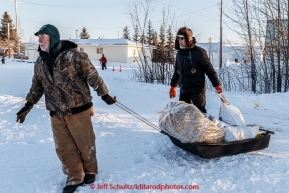 John Hooley and Andrew Huntington food bags and straw to a musher in the evening at the Galena checkpoint on Thursday March 12, 2015 during Iditarod 2015.  (C) Jeff Schultz/SchultzPhoto.com - ALL RIGHTS RESERVED DUPLICATION  PROHIBITED  WITHOUT  PERMISSION