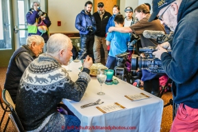 Jeff King shares his Millenium Hotel first musher to the Yukon dinner award with Paddy Nollner as the press looks on at Galena on Thursday March 12, 2015 during Iditarod 2015.  Paddy is the son of original 1925 serum musher Edgar Nollner.  (C) Jeff Schultz/SchultzPhoto.com - ALL RIGHTS RESERVED DUPLICATION  PROHIBITED  WITHOUT  PERMISSION