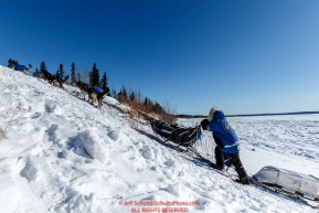 Paige Drobny runs up the steep river bank from the Yukon River to the Galena checkpoint on Saturday March 12th during the 2016 Iditarod.  Alaska    Photo by Jeff Schultz (C) 2016  ALL RIGHTS RESERVED