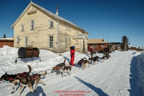 Nathan Schroeder runs down the road into the Nulato checkpoint past an old convent, turned thrift store, on Saturday afternoon March 12th during the 2016 Iditarod.  Alaska    Photo by Jeff Schultz (C) 2016  ALL RIGHTS RESERVED