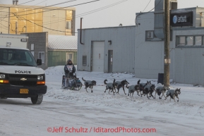 Paige Drobny runs along Front Street with a police escort on her way to the finish line in Nome on Wednesday March 12, during the 2014 Iditarod Sled Dog Race.PHOTO (c) BY JEFF SCHULTZ/IditarodPhotos.com -- REPRODUCTION PROHIBITED WITHOUT PERMISSION