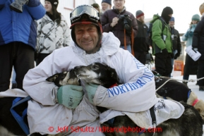 Martin Buser hugs his lead dogs, litter-mates Flash and Quick, at the finish line in Nome on Wednesday March 13, 2013. Iditarod Sled Dog Race 2013Photo by Jeff Schultz copyright 2013 DO NOT REPRODUCE WITHOUT PERMISSION