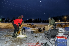 Volunteer veterinarians Scott Rosenbloom and Bruce Pedersen are given a dropped dog from Geir Idar Hjelvik in the early morning at the Kaltag checkpoint on Sunday March 13th during the 2016 Iditarod.  Alaska    Photo by Jeff Schultz (C) 2016  ALL RIGHTS RESERVED