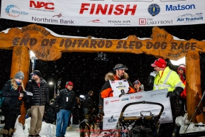 Pete Kaiser recieves his winning check, albeit blank, from GCI representive Bob James at the Nome finish line after winning the 2019 Iditarod Trail Sled Dog Race. Pete's winning time is 9 days 12 hours 39 minutes and 6 secondsPhoto by Jeff Schultz/  (C) 2019  ALL RIGHTS RESERVED