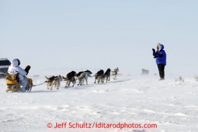 Matt Giblin waves to Donlin Gold representative Sue Gamache as he crosses the Nome road a few miles from Nome in 30 mph winds on Thursday March 14, 2013 during the Iditarod Sled Dog Race 2013Photo by Jeff Schultz copyright 2013 DO NOT REPRODUCE WITHOUT PERMISSION