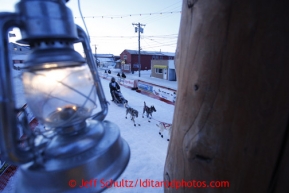 The Widows Lamp, lit until the last musher reaches Nome hangs from the burled finish line arch in as Paige Drobny runs down the finish line in 34th place on Thursday March 14, 2013. Iditarod Sled Dog Race 2013Photo by Jeff Schultz copyright 2013 DO NOT REPRODUCE WITHOUT PERMISSION