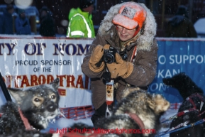 Iditarod fan Carolyn Drake takes a photo of a Charlie Benja dog at the Nome finish chute Friday March 14 during the 2014 Iditarod Sled Dog Race.PHOTO (c) BY JEFF SCHULTZ/IditarodPhotos.com -- REPRODUCTION PROHIBITED WITHOUT PERMISSION