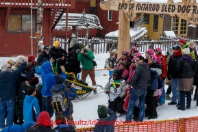 A crowd of K-9 Fairies gathers around Newton Marshall for a group photo in the finish chute after he arrived in 43rd place in Nome on Friday March 14 during the 2014 Iditarod Sled Dog Race.PHOTO (c) BY JEFF SCHULTZ/IditarodPhotos.com -- REPRODUCTION PROHIBITED WITHOUT PERMISSION