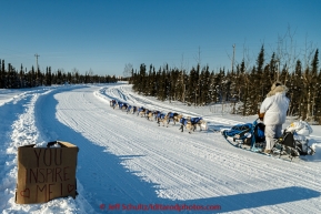 Tim Hunt runs down the road past one of several welcome signs on his way into the Huslia checkpoint on Saturday  March 14, 2015 during Iditarod 2015.  (C) Jeff Schultz/SchultzPhoto.com - ALL RIGHTS RESERVED DUPLICATION  PROHIBITED  WITHOUT  PERMISSION