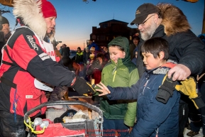 Aliy Zirkle gives away a dog bootie to a young fan in the finish chute in Nome after finishing in 15th place on Wednesday March 14th during the 2018 Iditarod Sled Dog Race.  Photo by Jeff Schultz/SchultzPhoto.com  (C) 2018  ALL RIGHTS RESERVED