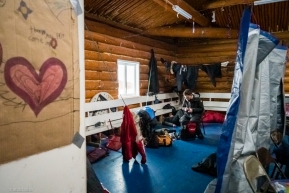 Inside mushers are drying out gear and sleeping under benches at the checkpoint in Ruby, Alaska.