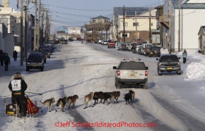 Thursday March 15, 2012   Lance Mackey comes off the trail and onto Front Street escorted by the police vehicle toward the finish in Nome. Iditarod 2012.