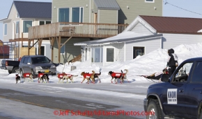 Thursday March 15, 2012   Ed Stielstra runs down Front Street in Nome with the KNOM radio spotter vehicle following him in and reporting his whereabouts just prior to the finish line . Iditarod 2012.