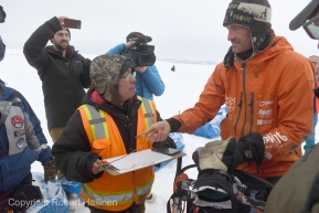 Kermit Ivanoff checks in Thomas Waerner at the Unalakleet, AK Iditarod checkpoint  in first place on Sunday, March 15, 2020. (Photo by Bob Hallinen)