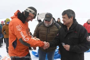 Thomas Waerner accepts the Ryan Air first to the coast award from Allen Ivanoff at the Unalakleet, AK Iditarod checkpoint after arriving in first place on Sunday, March 15, 2020. The award is $2,000 worth of gold nuggets. In the middle is race marshal Mark Nordman. (Photo by Bob Hallinen)