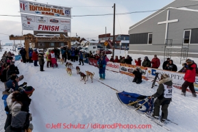 Marcelle Fressineau runs into the finish chute to claim 49th and last place at Nome as Lisbet Norris arrived just a minute before her on Saturday March 15 during the 2014 Iditarod Sled Dog Race.PHOTO (c) BY JEFF SCHULTZ/IditarodPhotos.com -- REPRODUCTION PROHIBITED WITHOUT PERMISSION