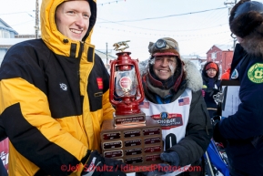 Wells Fargo Bank Nome store manager, Tyler Hull, presents Marcelle Fresineau with the red lantern last place award at the finish line shorlt after she finished in 49th place on Saturday March 15 during the 2014 Iditarod Sled Dog Race.PHOTO (c) BY JEFF SCHULTZ/IditarodPhotos.com -- REPRODUCTION PROHIBITED WITHOUT PERMISSION