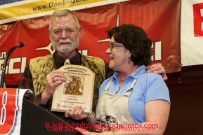 Greg Bill is honored with the Herbie Nayokpuk spirit of the Iditarod award as he retires after his 42 years of working with the Iditarod at the musher 's finishers banquet in Nome.  His wife Annie at his side. Sunday March 16 after the 2014 Iditarod Sled Dog Race.PHOTO (c) BY JEFF SCHULTZ/IditarodPhotos.com -- REPRODUCTION PROHIBITED WITHOUT PERMISSION