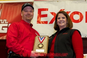 ExxonMobil representative Karen Hagedorn presents Aaron Burmeister with the ExxonMobil Musher's Choice Award at the musher 's finishers banquet in Nome on Sunday March 16 after the 2014 Iditarod Sled Dog Race.PHOTO (c) BY JEFF SCHULTZ/IditarodPhotos.com -- REPRODUCTION PROHIBITED WITHOUT PERMISSION