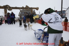 Christine Roalofs runs into the chute and across the finish line to finish in last place and is the winner of the Red Lantern Award on Front Street in Nome.  Iditarod Sled Dog Race 2013Photo by Jeff Schultz copyright 2013 DO NOT REPRODUCE WITHOUT PERMISSION