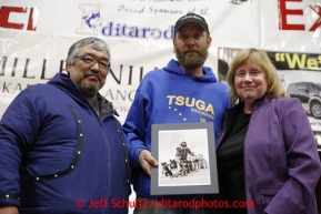 Mike Ellis (center) receives the Leonhard Seppala Heritage Grant award from Mike Williams and Laura Samuelson at the musher awards banquet in Nome on Sunday March 17, 2013.  Iditarod Sled Dog Race 2013Photo by Jeff Schultz copyright 2013 DO NOT REPRODUCE WITHOUT PERMISSION