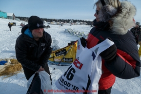 Dallas Seavey recieves his race bib from checker Beverly Andersson just before leaving the White Mountain checkpoint on Tuesday March 16, 2015 during Iditarod 2015.  (C) Jeff Schultz/SchultzPhoto.com - ALL RIGHTS RESERVED DUPLICATION  PROHIBITED  WITHOUT  PERMISSION