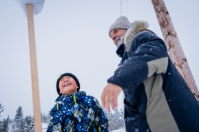 Bill Sampson, a Koyuk checkpoing veterinarian, and a yound Koyuk resident play at balancing snow on a stick.  March 17, 2020