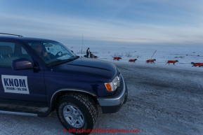 Ken Anderson on the trail several miles from the Nome finish line passes the KNOM radio station spotter vehicle manned by Ric Schmidt on Wednesday March 18, 2015 during Iditarod 2015.  (C) Jeff Schultz/SchultzPhoto.com - ALL RIGHTS RESERVED DUPLICATION  PROHIBITED  WITHOUT  PERMISSION