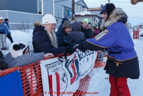 Ken Anderson's wife Gwenn hands out dog booties shorlty after Ken finished at the Nome finish line on Wednesday March 18, 2015 during Iditarod 2015.  (C) Jeff Schultz/SchultzPhoto.com - ALL RIGHTS RESERVED DUPLICATION  PROHIBITED  WITHOUT  PERMISSION