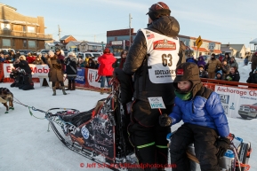 Aaron Burmeister's son Hunter rides on the sled caboose as Aaron runs his team to the dog lot after finishing in third place at the Nome finish line on Wednesday March 18, 2015 during Iditarod 2015.  (C) Jeff Schultz/SchultzPhoto.com - ALL RIGHTS RESERVED DUPLICATION  PROHIBITED  WITHOUT  PERMISSION
