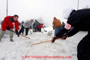 Volunteers shovel snow back onto the track at the ceremonial start of the Iditarod sled dog race Anchorage Saturday, March 2, 2013. Photo (C) Jeff Schultz/IditarodPhotos.com  Do not reproduce without permission