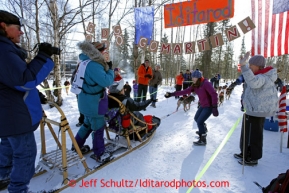 Libby Kugel hands a muffin to Angie Taggart at the ' Muffin checkpoint ' along the bike trail during the ceremonial start of the Iditarod sled dog race Anchorage Saturday, March 2, 2013. Photo (C) Jeff Schultz/IditarodPhotos.com  Do not reproduce without permission