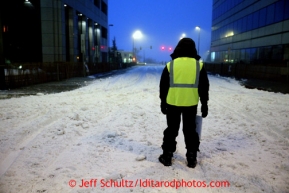 Parking volunteer Sue Mattson waits paitently in thee early morning hours on 4th avenue to guide dog mushers onto the street prior to the ceremonial start of the Iditarod sled dog race in downtown Anchorage Saturday, March 2, 2013. Photo (C) Jeff Schultz/IditarodPhotos.com  Do not reproduce without permission