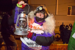 Mary Helwig at the Nome finish line holds up the Widow's lamp during the 2016 Iditarod.  Alaska    

Photo by Jeff Schultz (C) 2016  ALL RIGHTS RESERVED