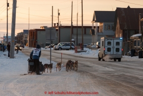 Becca Moore runs on Front Street with a police escort just a mile from the finish line in Nome on Saturday March 21, 2015 during Iditarod 2015.  (C) Jeff Schultz/SchultzPhoto.com - ALL RIGHTS RESERVED DUPLICATION  PROHIBITED  WITHOUT  PERMISSION