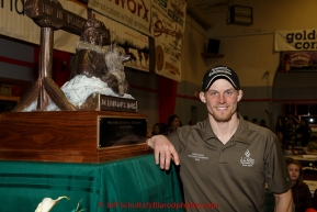 2015 Iditarod champion Dallas Seavey poses next to the Joe Redington Sr. first place trophy at the finishers banquet in Nome on Sunday  March 22, 2015 during Iditarod 2015.  (C) Jeff Schultz/SchultzPhoto.com - ALL RIGHTS RESERVED DUPLICATION  PROHIBITED  WITHOUT  PERMISSION