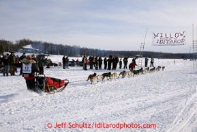 Jason Mackey passes a group of picnicers on Long Lake after leaving the restart of the Iditarod sled dog race in Willow, Alaska Sunday, March 3, 2013.