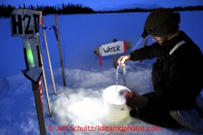 Nicolas Petit of Girdwood gets water from the hole in Finger Lake at the checkpoint Monday, March 4, 2013.