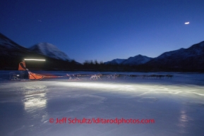 Jake Berkowitz streaks across the glare ice of the Tatina River in the late evening on his way to Rohn on Monday March 3 during Iditarod 2014 . PHOTO BY JEFF SCHULTZ/IDITARODPHOTOS.COM  USE ONLY WITH PERMISSION