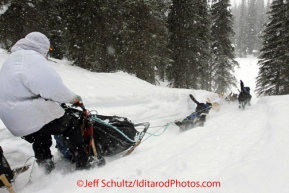 Monday March 5, 2012 Martin Buser takes his foot off the runners to balance as his team heads down a hill away from the Finger Lake checkpoint during Iditarod 2012.