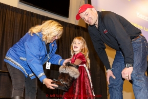 Ken Anderson's daughter Lily chooses his starting postion number from a mukluk held by Jan Halstead of Donlin Gold at the musher banquet & drawing on Thursday March 5, 2015 at the Denaina Center in Anchorage, Alaska.  Iditarod 2015 (C) Jeff Schultz/SchultzPhoto.com - ALL RIGHTS RESERVED DUPLICATION  PROHIBITED  WITHOUT  PERMISSION