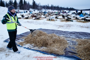 Volunteer Michelle Keagle rakes used dog straw at the Finger Lake checkpoint during the 2018 Iditarod race on Monday March 05, 2018. Photo by Jeff Schultz/SchultzPhoto.com  (C) 2018  ALL RIGHTS RESERVED