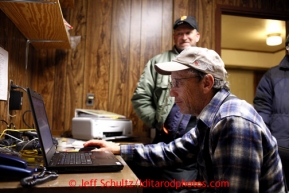 Volunteer comms Jim Lawson mans the comupter while Troy Zachary looks on at the Tokotna checkpoint March 6, 2013.Iditarod Sled Dog Race 2013Photo by Jeff Schultz copyright 2013 DO NOT REPRODUCE WITHOUT PERMISSION