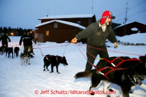 Volunteers walk the dogs as they help park Mike Williams team at the Tokotna checkpoint just before dawn on Wednesday March 6, 2013.Iditarod Sled Dog Race 2013Photo by Jeff Schultz copyright 2013 DO NOT REPRODUCE WITHOUT PERMISSION