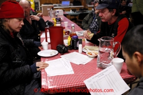 With the race standings in hand, Aliy Zirkle, Aaron Burmeister, Allen Moore and Mike Williams Jr. talk race strategy at the Tokotna checkpoint during their 24 hour layover on Wednesday March 6, 2013.Iditarod Sled Dog Race 2013Photo by Jeff Schultz copyright 2013 DO NOT REPRODUCE WITHOUT PERMISSION