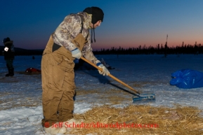 Donlin Gold employee and volunteer Ricky Ciletti rakes up used straw at the Cripple checkpoint, Thursday, March 6, during the Iditarod Sled Dog Race 2014.PHOTO (c) BY JEFF SCHULTZ/IditarodPhotos.com -- REPRODUCTION PROHIBITED WITHOUT PERMISSION